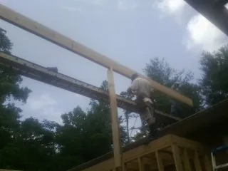 Carpenter setting a ridge beam over a new addition frame — Ice Dam Removal by Roofing Brothers in Newland