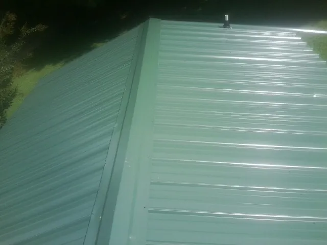 New green metal panels meeting at the ridge of a roof — Flat Roof Repair work by our crew in Newland