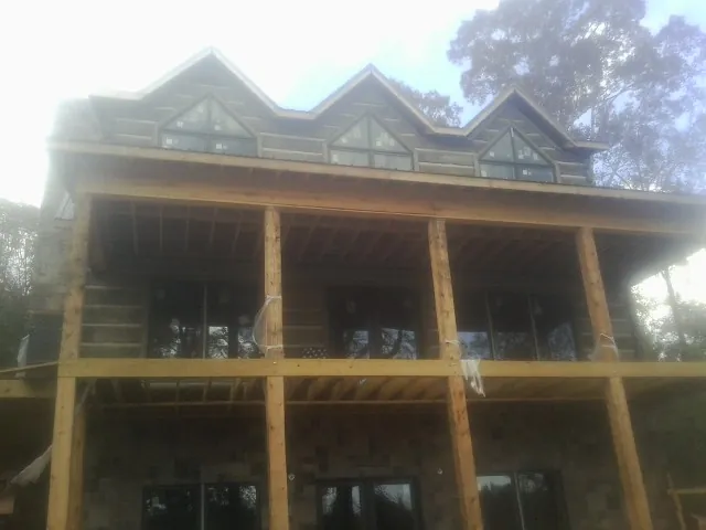 Dormers and porch framing on a large log home under construction — Roof Coating work by our crew in Newland