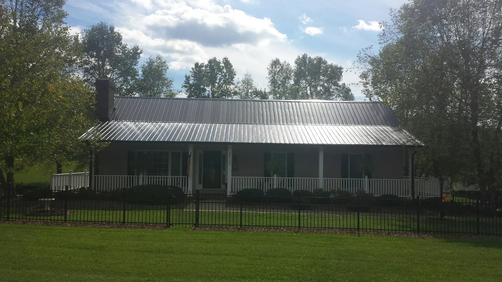 Gray metal roof on a brick ranch with a full width front porch — Gutter Guard Installation work by our crew in Newland
